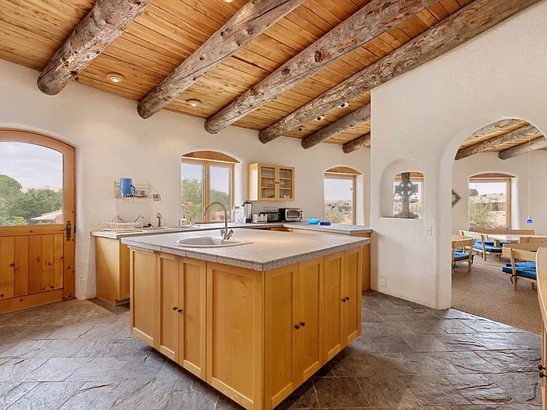 Kitchen with exposed vigas and red cedar, stone tile countertops, maple wood cabinets and natural random tile stone floor