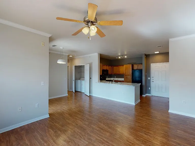 Apartment kitchen, dining and living room with wood-style flooring.