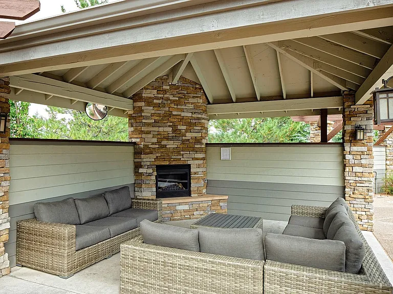 Relax in style at this elegant outdoor lounge, featuring a cozy fireplace and plush seating.