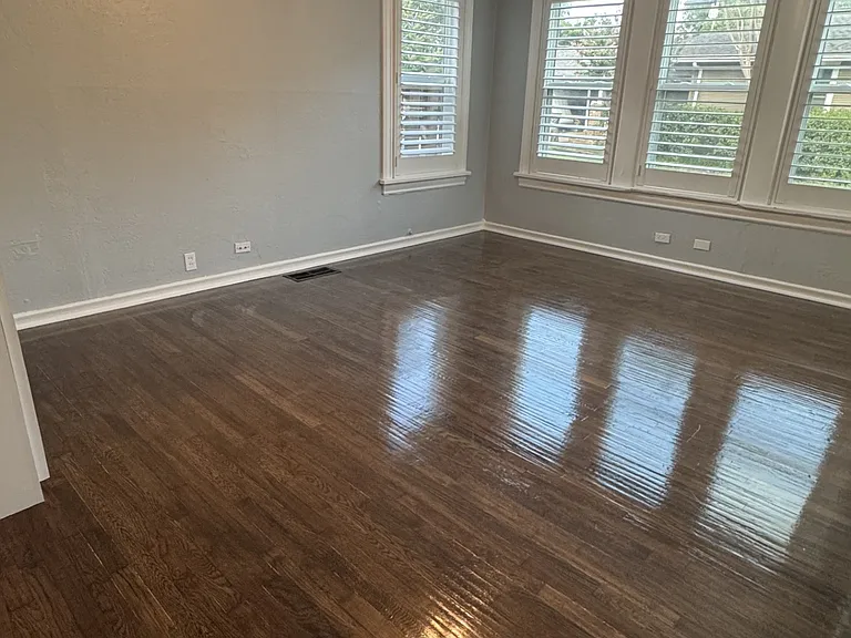 View of bedroom with gorgeous hand scrapped hardwood floors, custom wood plantation shutters, and ample lighting.