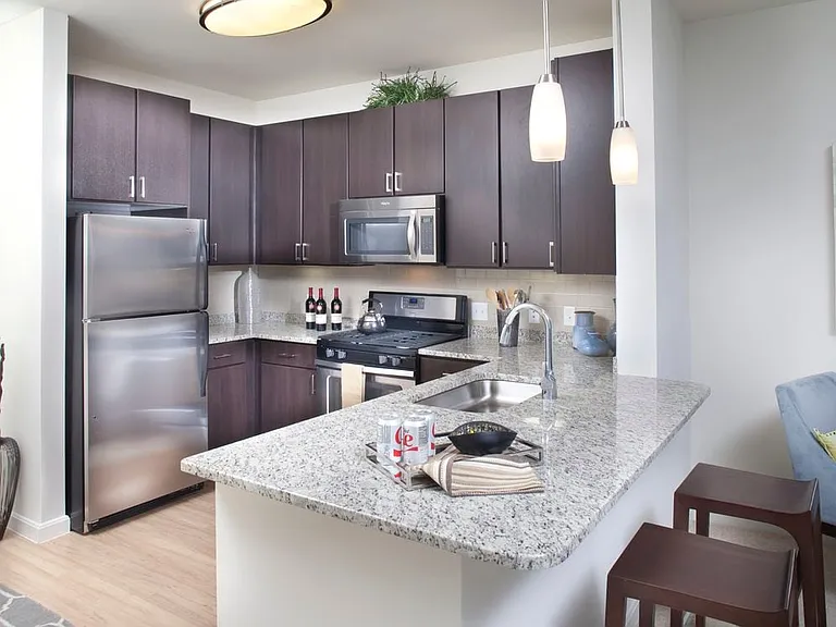 Classic Package kitchen with stainless steel appliances, white speckled granite countertops, espresso cabinetry, beige tile backsplash, and hard surface flooring