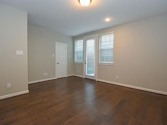 Nice size first floor bedroom with neutral paint, window blind with access to the back patio.