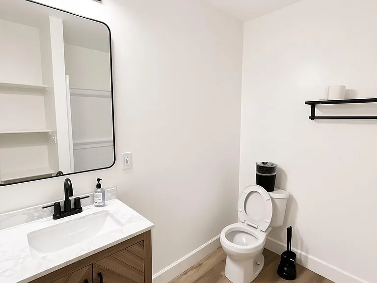 Updated bath with single-sink vanity, contemporary fixtures, and convenient open shelving for everyday storage.