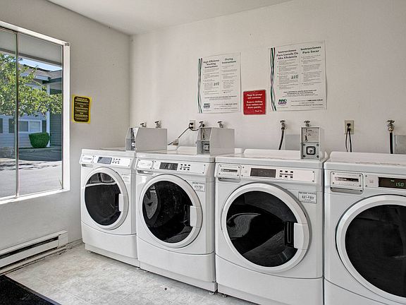 A shared laundry room with multiple coin operated washers and dryers