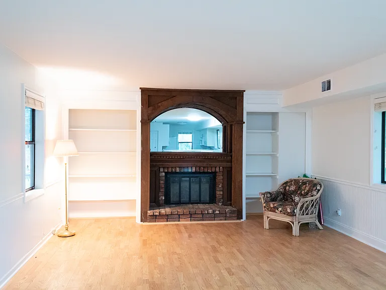 To the left, on the east side of the room, you see a gas log fireplace, book shelves, and space for a living or TV area.