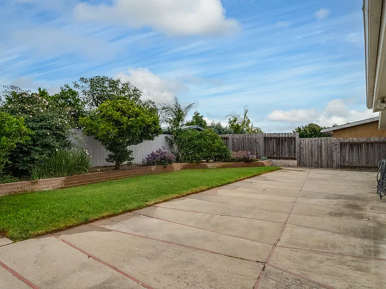 Fully fenced backyard with landscaping, grass, and concrete area. Fruit trees (lemon, orange, and lime)!