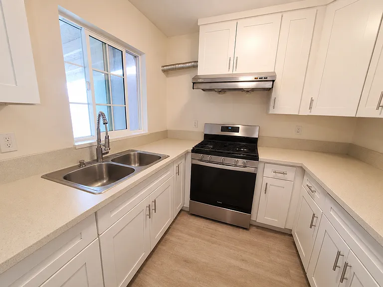 Kitchen with double sinks, clean cabinets, and full size gas stove.