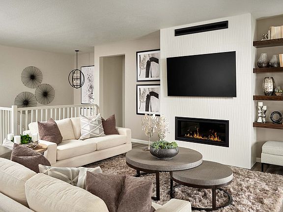 A cozy and modern living room with a white sofa, a fireplace, and a large TV mounted on the wall, su