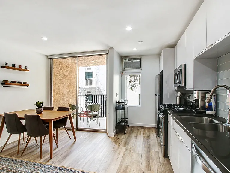 Furnished open kitchen with black quartz countertops, stainless steel appliances, recessed lights