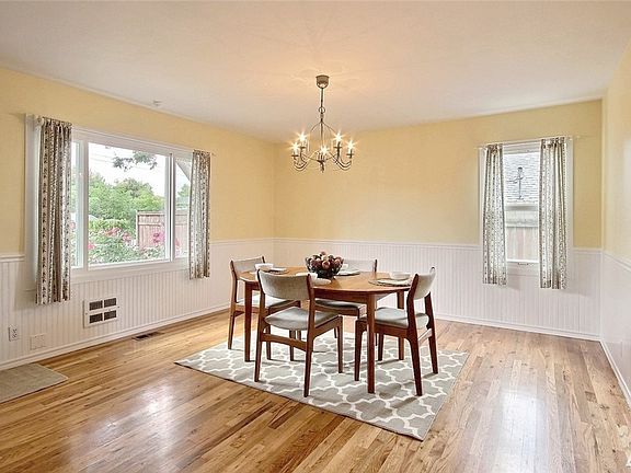 Large dining room with gleaming hardwoods and elegant wainscoting. 