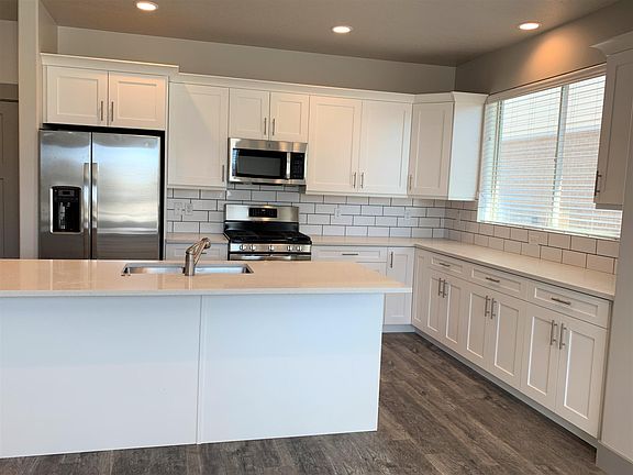 Kitchen has gas range, quartz countertops and tile backsplash