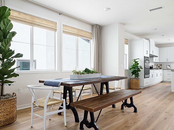 A bright and airy kitchen-dining area with a wooden dining table, bench, and chairs, surrounded by l