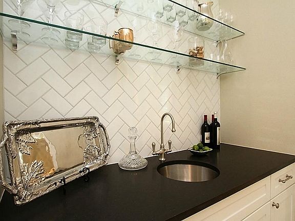 The wet bar showcases black honed granite, subway tile backsplash, custom cabinets with soft close drawers, built-in ice maker, glass display shelving...