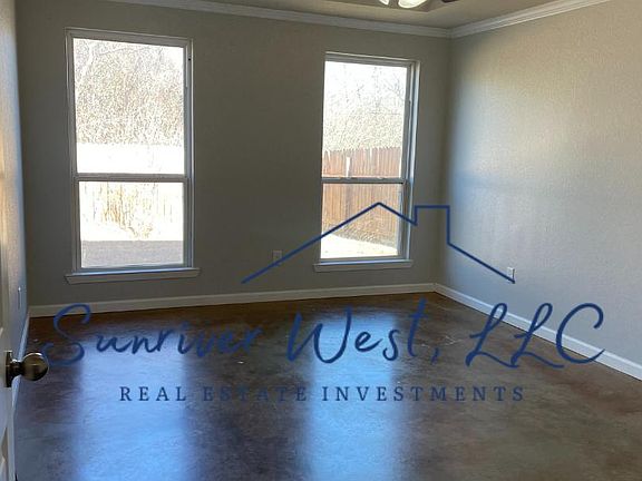 Primary bedroom with tray ceiling, windows to fenced backyard.