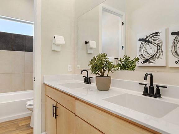Secondary bathroom at the front of the home features a double vanity and shower tub combo.