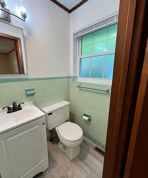 Updated bathroom with charming vintage character and modern touches throughout. Features include a spacious glass-enclosed shower combination, updated vanity with modern fixtures, stylish lighting, and durable flooring. The soft mint tile accents add uniq
