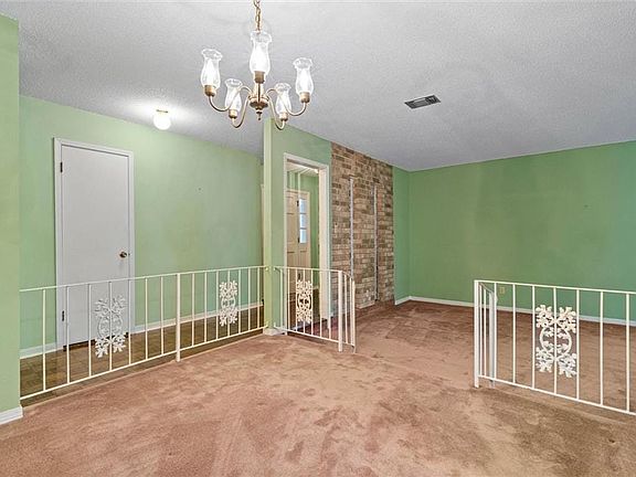 Carpeted spare room with visible vents, baseboards, and an inviting chandelier