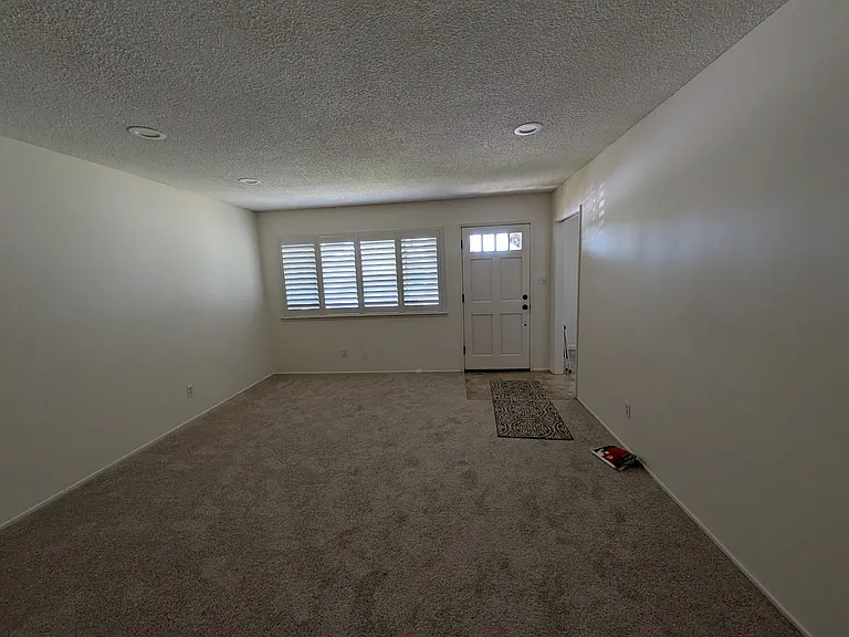 Large living room with plantation shutters, new carpet throughout, and freshly painted.