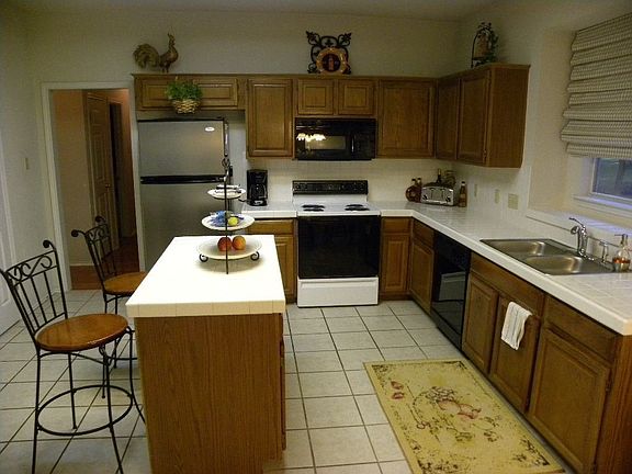 Open kitchen with tile counter tops. Stainless refrigerator conveys!