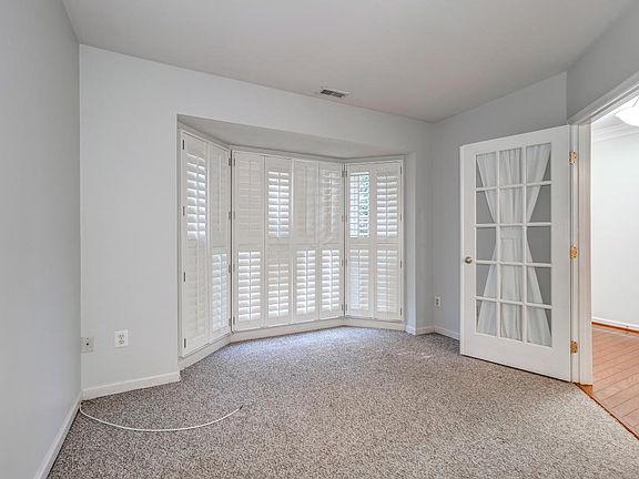 Entry level bedroom/office/playroom with plantation shutters and doors has a 1/2 bath