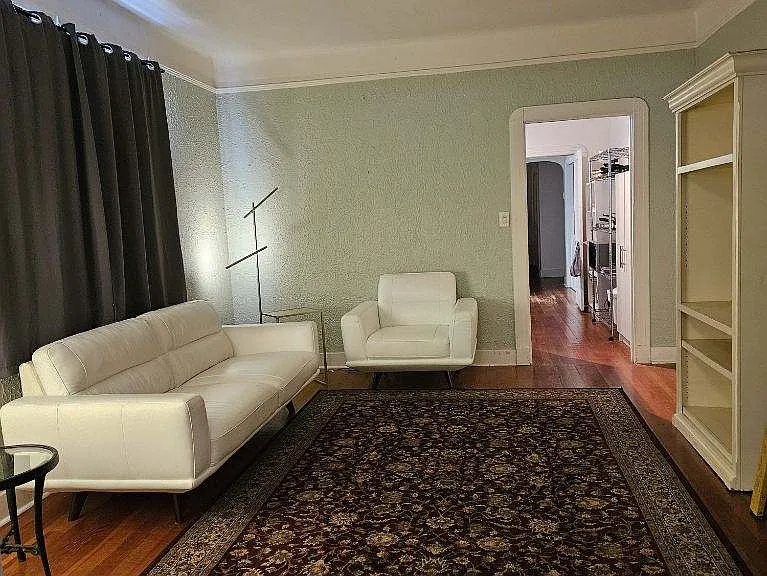 Living room leads into kitchen. Window treatments included.