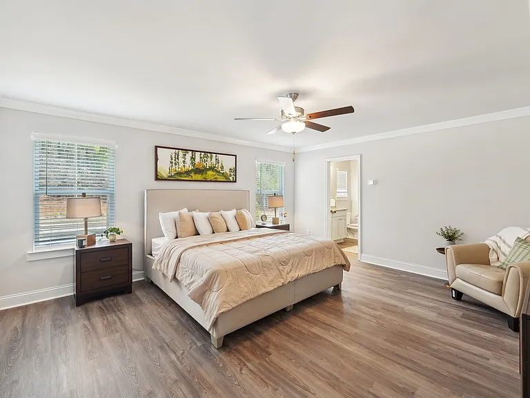 Another view of the spacious primary suite showcasing a grand bed and modern ceiling fan.