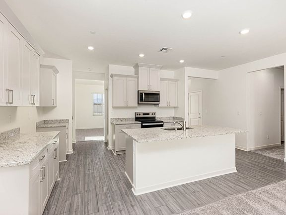 The kitchen has stainless steel appliances and plank flooring.