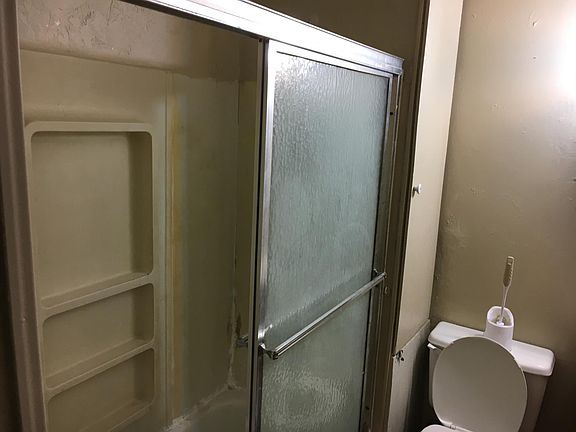 tub shower in bathroom with toilet. Also linen closet to left of toilet.