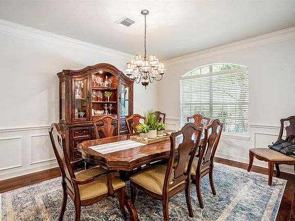 The formal dining room has a wood flooring, chair and crown molding and a beautiful arched window that allows for natural lighting.