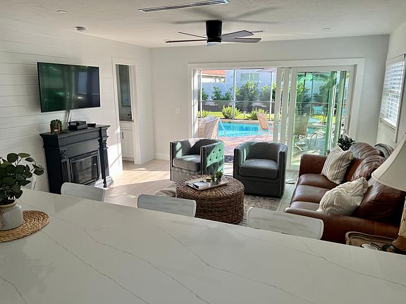 Open concept floor plan, View from kitchen in living room and 3-panel sliding door to screened-in pool.