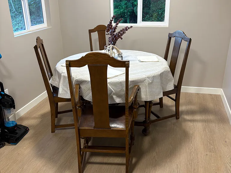 Dedicated dining nook with a round table for four, set beside large windows with calming views of surrounding greenery.