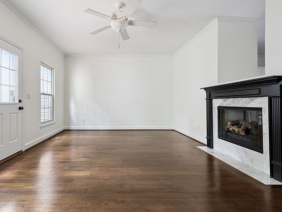 The spacious living room features a gas fireplace, wood floors, and access to the back deck.