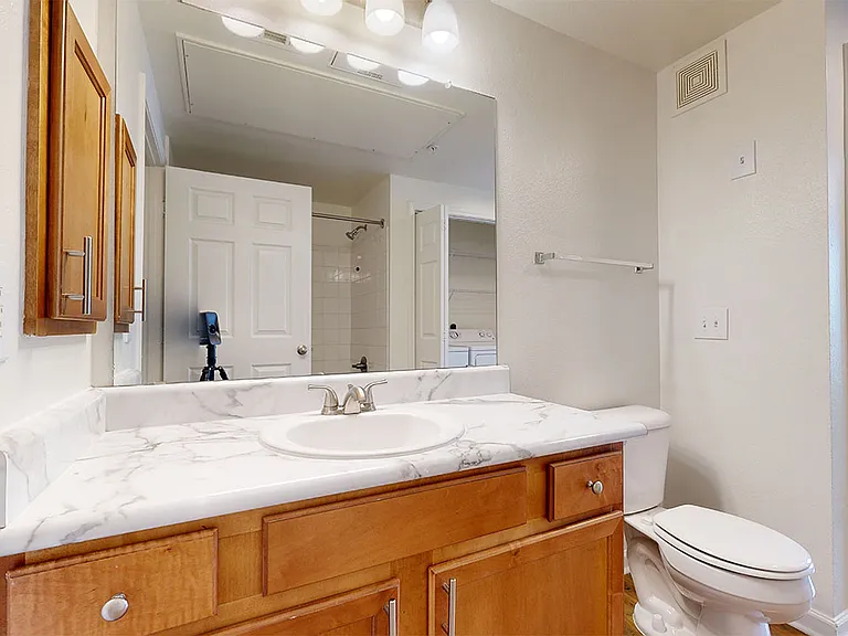 Apartment bathroom with wood-style flooring and marble-style countertops (shown here). Quartz-style countertops are available in select homes.