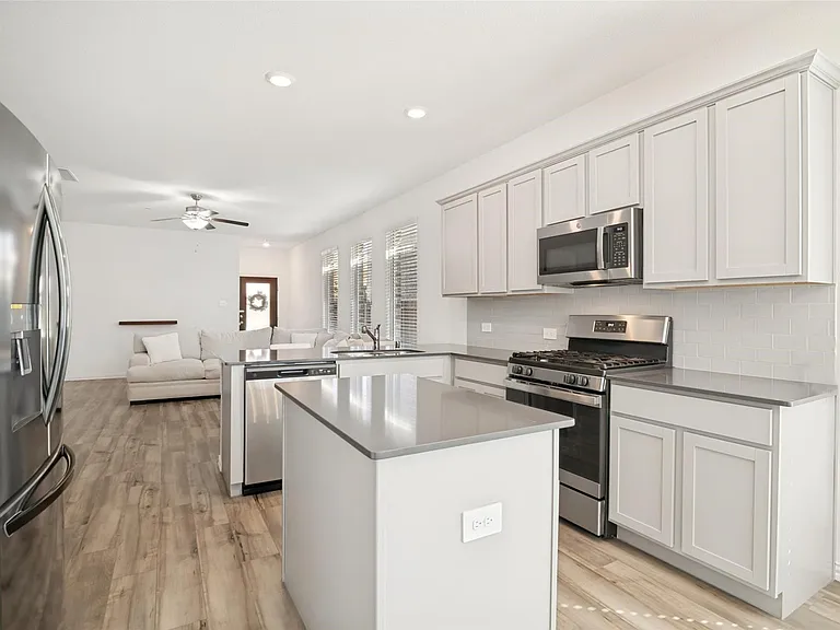 Kitchen featuring light-toned cabinetry, stainless steel appliances, a center island with countertop seating, and wood-finish flooring