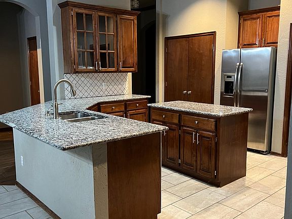 Kitchen with lots of countertop space, an island with electric outlets, double pantries, granite and updated stainless steel appliances. Huge skylight and high ceilings!
