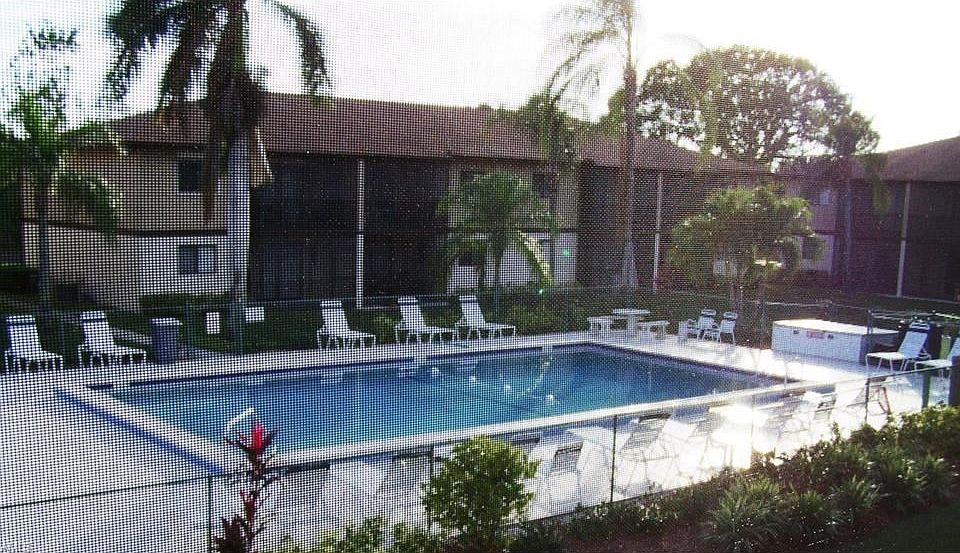View from the screened lanai of the southern community pool & landscaped grounds.  There are 2 community pools in the quiet comm