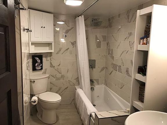 Tiled bathroom with whirlpool tub, rainfall shower, heated towel rack and floor