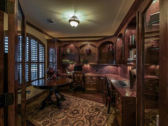 French doors lead into study that has gleaming hardwood floors, incredible built-in desks and ample custom cabinetry.
