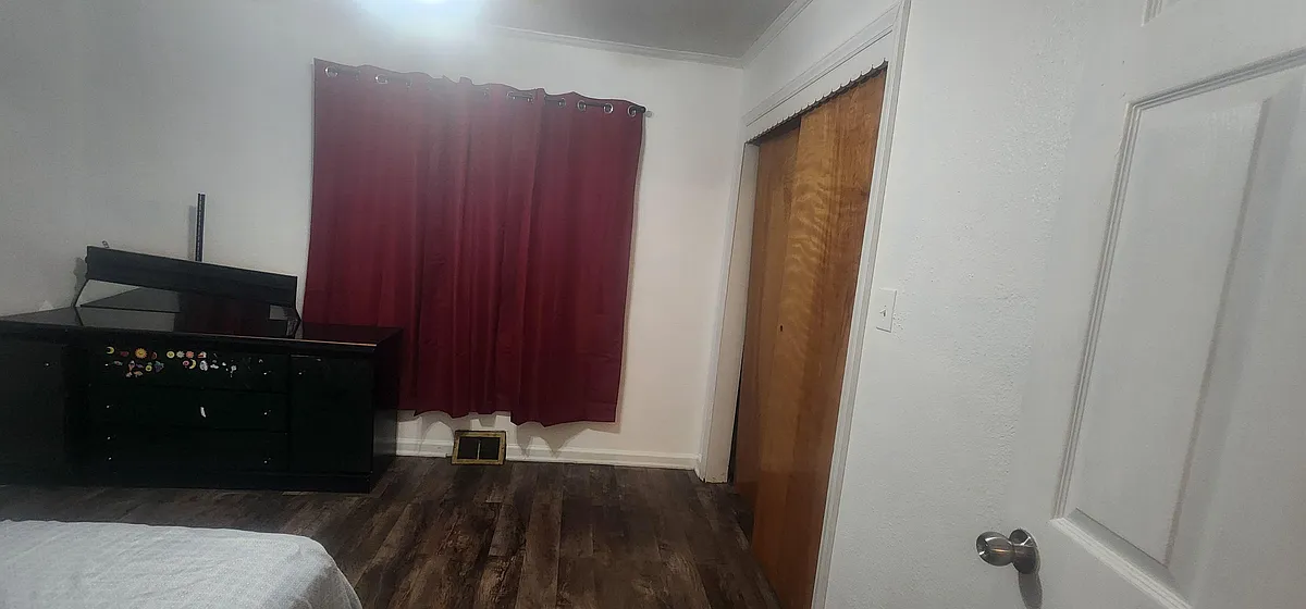 Bedroom with wood-look flooring, a window with curtain panels, and a closet for everyday storage. - NE 74th St
