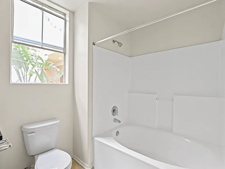 Bathroom with Window, Bathtub, and Cabinet Storage