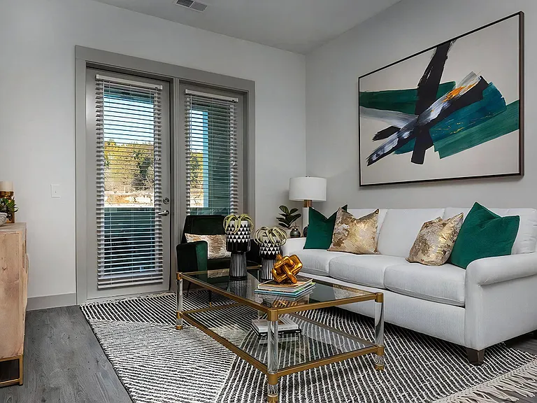 Chic Living Space Featuring White Sofa, Abstract Art, and Glass Coffee Table