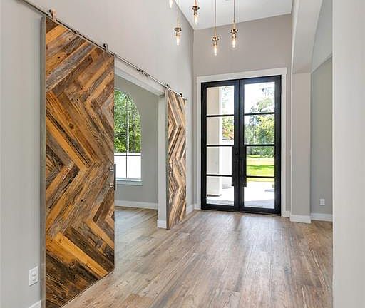 Custom wrought iron front double door and hand crafted barn doors leading to the study