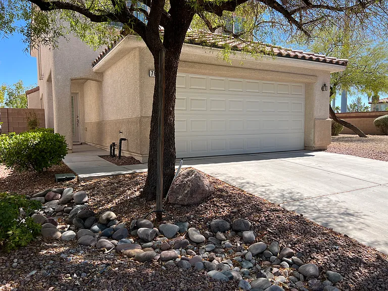 This home's landscaping is easy to maintain with minimal plants and one tree in the front and just decorative rock in the backyard.