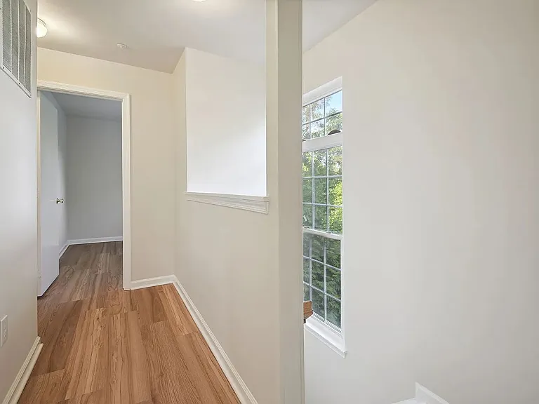 The view from landing at the top of the stairs showing more natural light from the large east-facing window and the floors connecting the living quarters on the upper level.