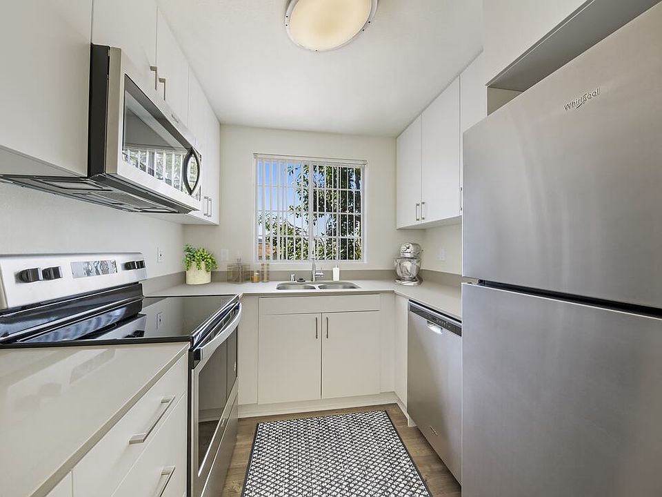 Renovated Package kitchen with white cabinetry, grey quartz countertops, stainless steel appliances, upgraded lighting and fixtures, and hard surface flooring throughout kitchen, dining area, and bath.