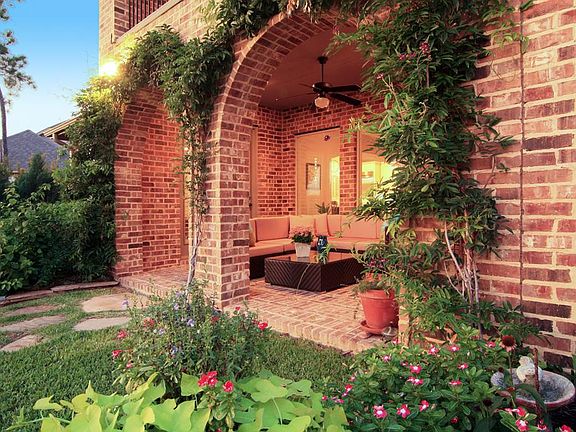 Wisteria covered brick archways at covered patio overlooking the back lawn and lake.