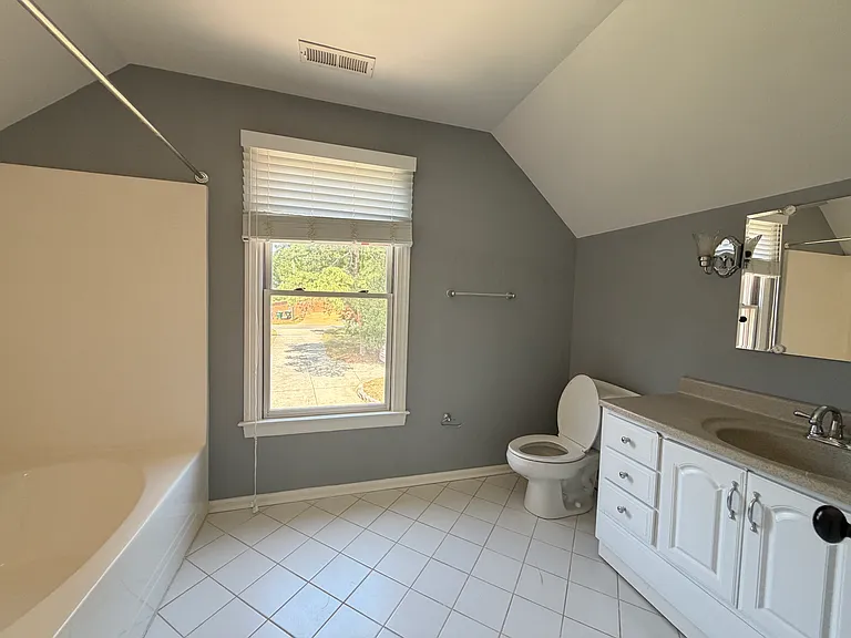 Bright full bath adjacent to the skylit bedroom, with soft natural light, clean tile floors and ample storage for guests or family use.