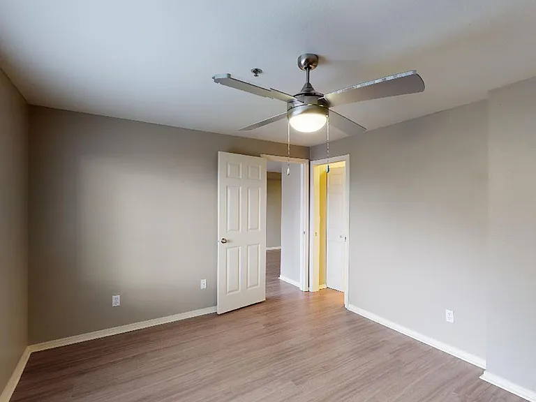 Spacious apartment bedroom with wood-style flooring.