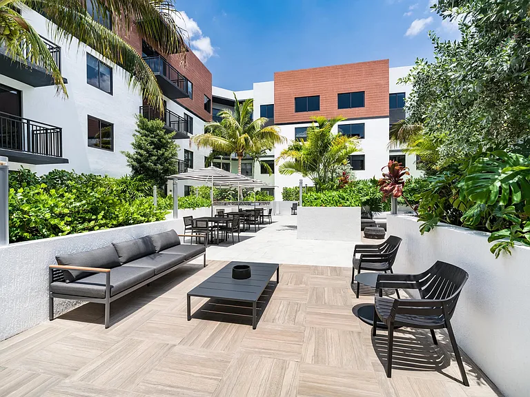 Palm-lined courtyard with outdoor seating, dining areas, and gathering spaces that bring everyday connection outdoors in Coral Springs.