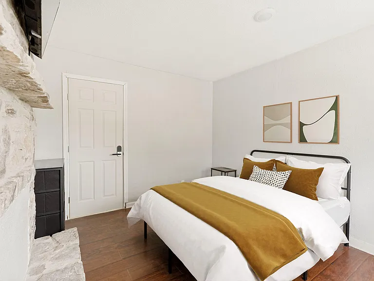 Well-appointed bedroom with a metal-frame bed, warm wood floors, and a convenient dresser for everyday storage.